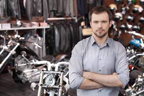 A motorcycle dealer stands in his shop
